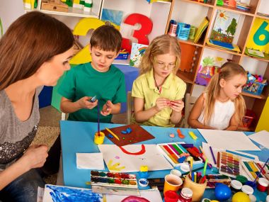 Kil çocuklar sınıfta modelleme hamuru. Okulda öğretmen öğretir.