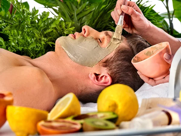 Máscara facial de barro de hombre en el salón de spa. Masaje con cara llena de barro . — Foto de Stock