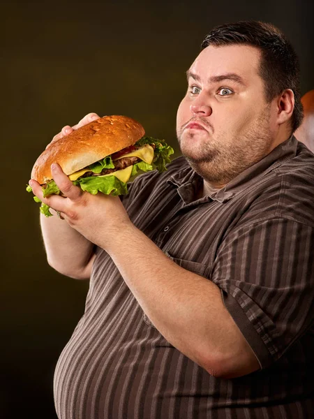 Fat man eating fast food hamberger. Breakfast for overweight person. Stock Photo