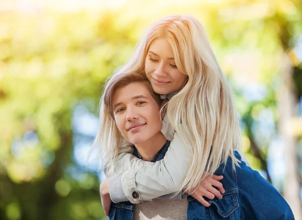 Paar knuffelen en flirten in voorjaar park en op zoek naar camera. — Stockfoto