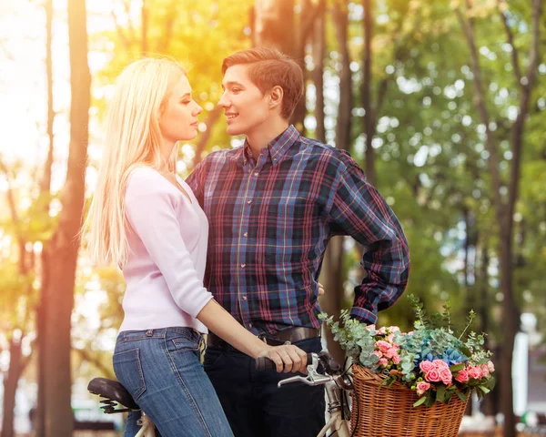 Liebespaar küsst sich auf Fahrrad und Frühlingsblumenkorb. — Stockfoto