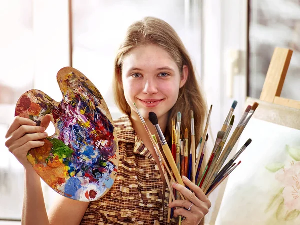 Художник рисует на мольберте в студии. Девушка рисует кисточкой . — стоковое фото