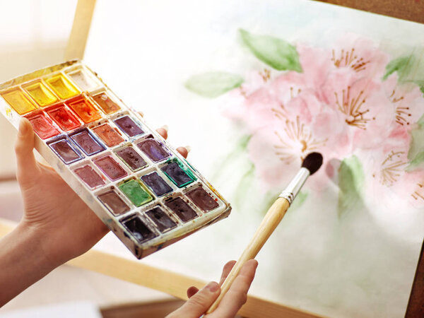 Artist painting on easel studio. Girl hands paints with brush.