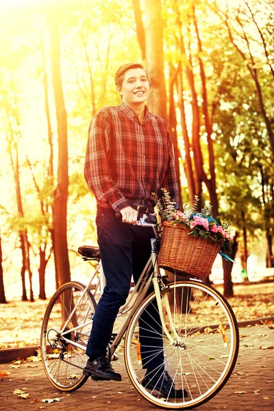 Homem de bicicleta com cesta de flores está montando parque de verão . — Fotografia de Stock