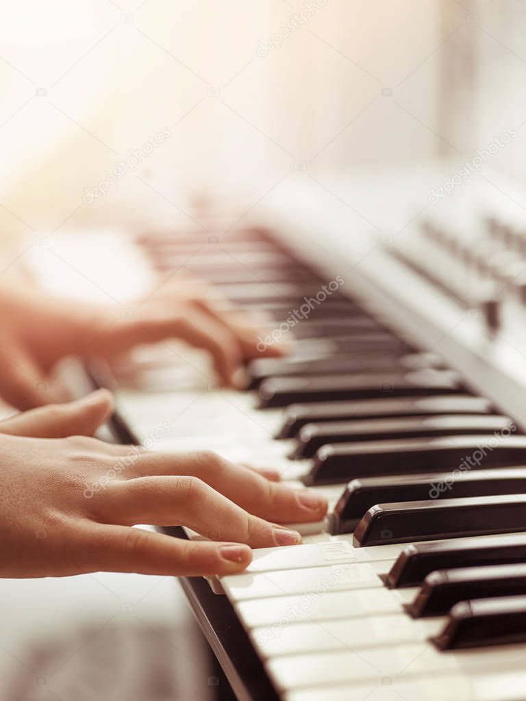 Midi keyboard or electronic piano and playing child hands.