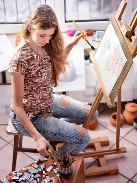 Künstler malen auf Staffelei im Atelier. Mädchen malt mit Pinsel. — Stockfoto