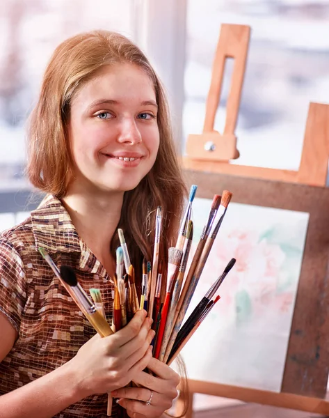 Künstler malen auf Staffelei im Atelier. Mädchen malt mit Pinsel. — Stockfoto