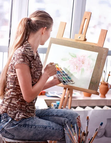 Künstler malen auf Staffelei im Atelier. Mädchen malt mit Pinsel. — Stockfoto