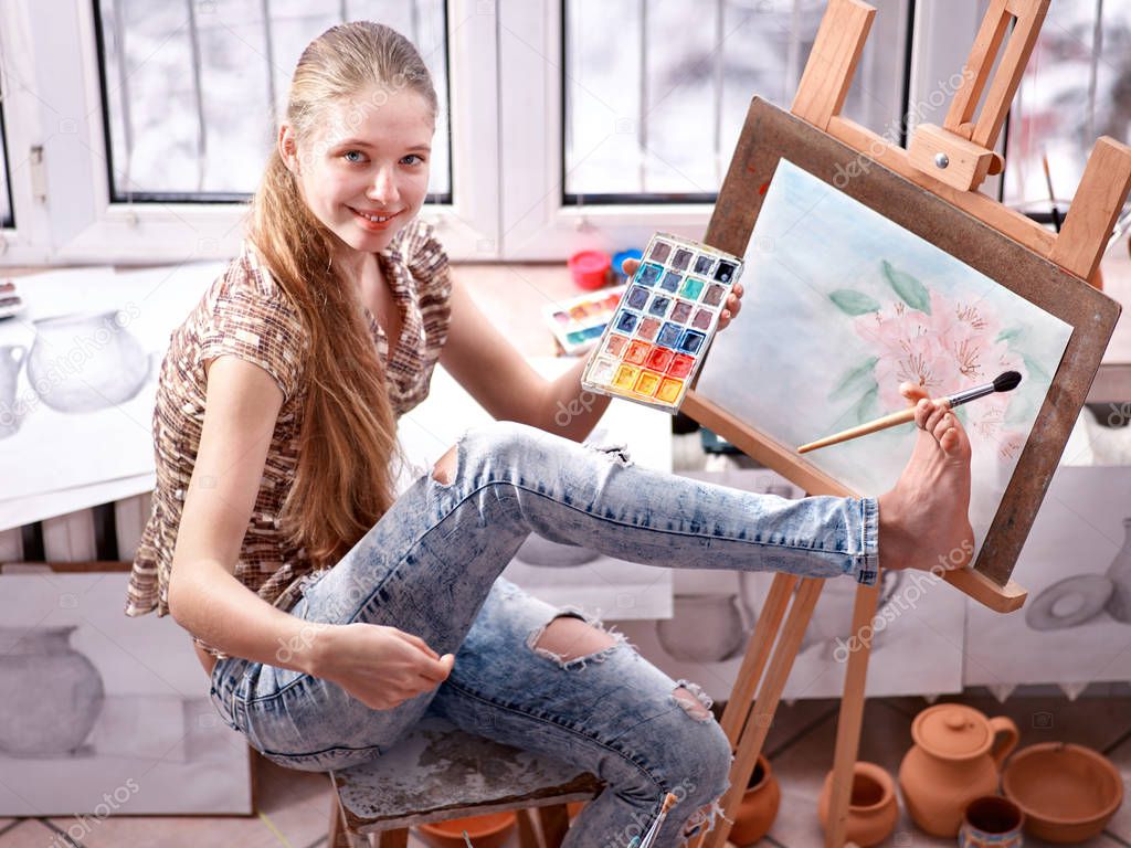 Artist painting on easel in studio. Girl paints with brush.