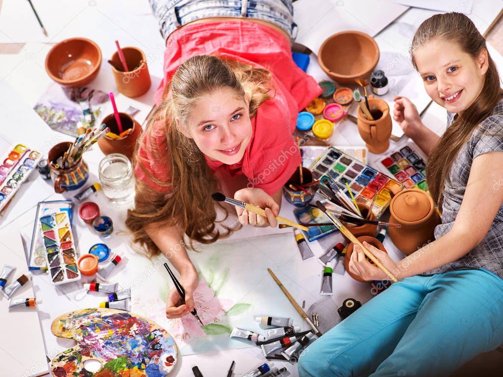 Authentic artist children girl paints on floor. Top view.