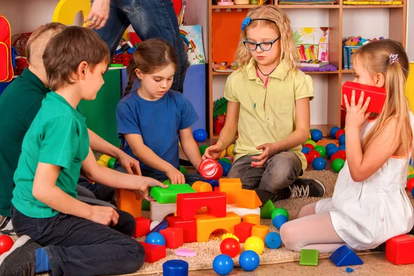 Bouwstenen van de kinderen in de kleuterschool. Groep kinderen spelen speelgoed vloer. — Stockfoto