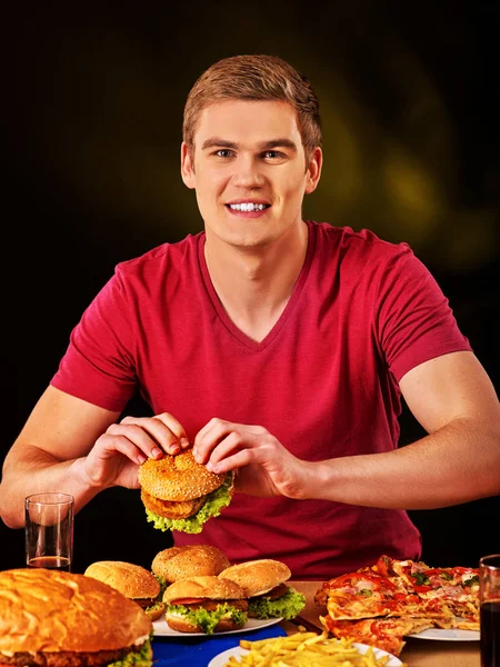 Mujer comiendo papas fritas y hamburguesa en la mesa . — Foto de Stock