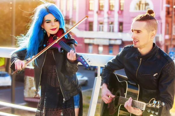 Woman and man perform music on violin city outdoor.