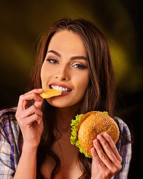 Mujer comiendo papas fritas y hamburguesa en la mesa . — Foto de Stock