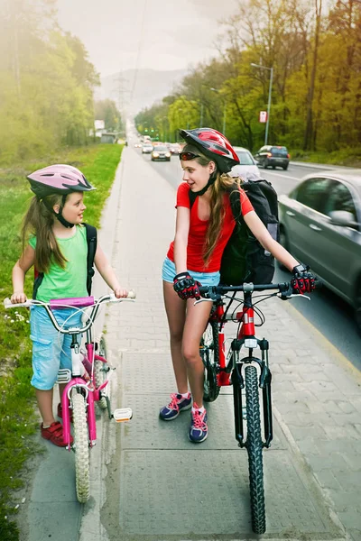 Mädchen, die auf dem gelben Radweg fahren. Es sind Autos auf der Straße. — Stockfoto