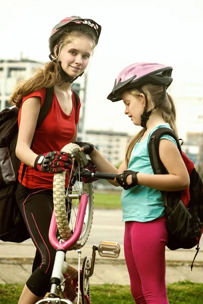 Bicycle tire pumping by child bicyclist. Girl repair bicycle on road .