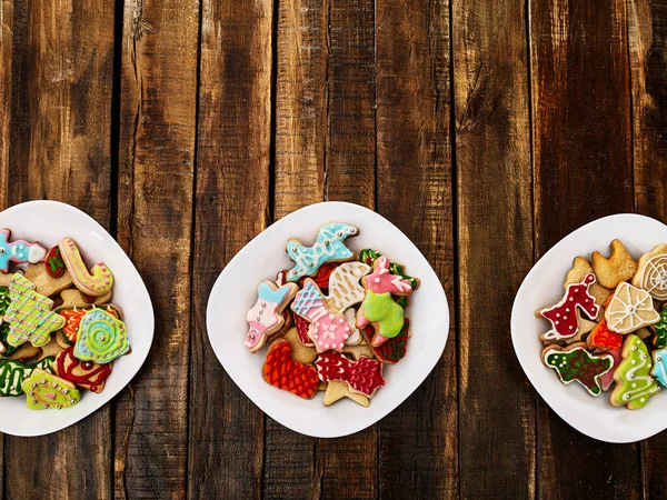 Galletas de jengibre de Navidad en tres platos por mesa de madera — Foto de Stock