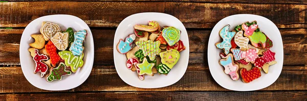Christmas gingerbread cookies on three plates by wooden table — Stock Photo, Image