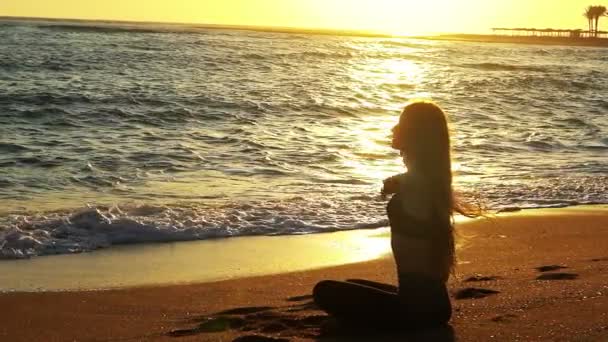 Sea yoga femme mains en l'air au soleil saluer position lotus — Video