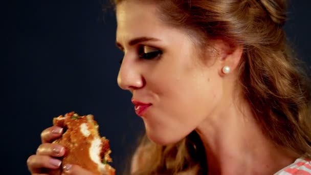 Uma rapariga a comer hambúrguer. Fast Food hambúrguer de mulher nibble flerte — Vídeo de Stock