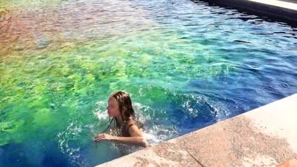 Slow motion girl sitting on pool side, fall and swimming — Stock Video