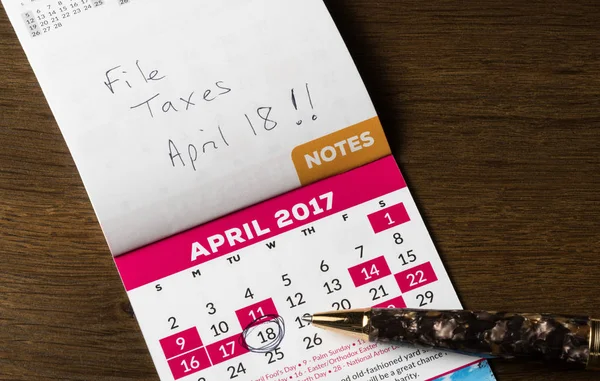 Gold pen laying on calendar for tax day — Stock Photo, Image