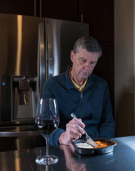 Solitario hombre mayor comiendo comida preparada en la mesa —  Fotos de Stock