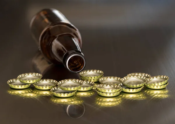 Glass bottle mouth behind a stack of metal caps — Stock Photo, Image