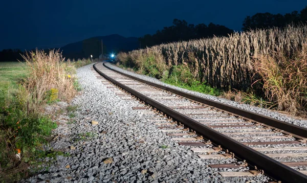 Tegemoetkomende trein onderaan steile sporen bij nacht — Stockfoto