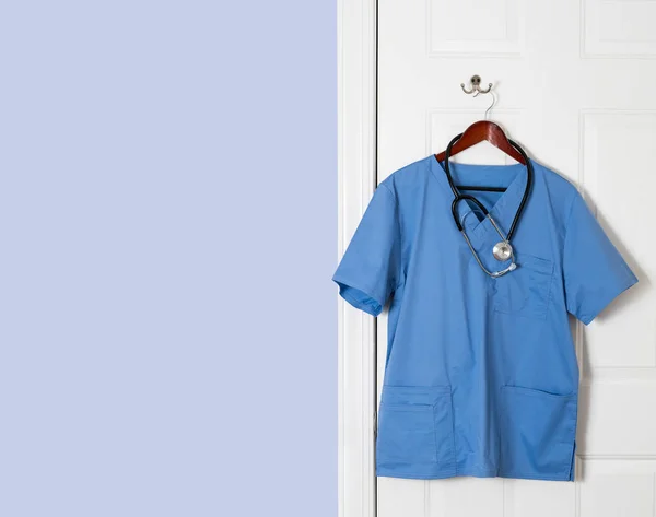 Camisa de lavado azul para profesionales médicos colgando en la puerta — Foto de Stock
