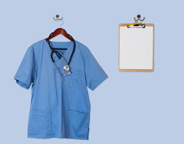 Blue scrubs shirt for medical professional hanging with clipboar — Stock Photo, Image