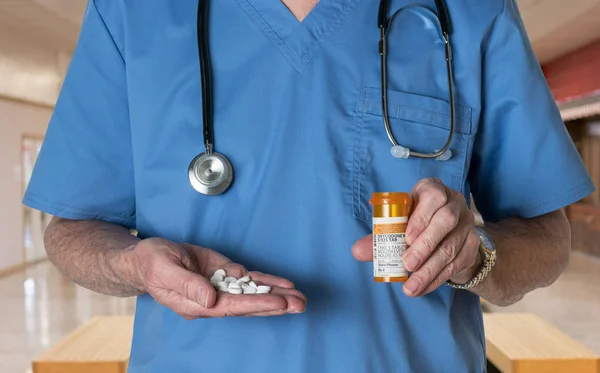 Старший врач в форме с таблетками оксикодона — стоковое фото