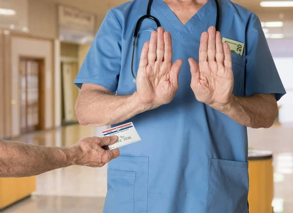 स्क्रब में सीनियर डॉक्टर मेडिकेयर कार्ड से इनकार कर रहा है — स्टॉक फ़ोटो, इमेज
