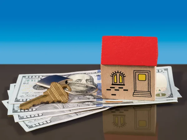 Игрушечный домик на долларовых купюрах США с ключом от двери — стоковое фото