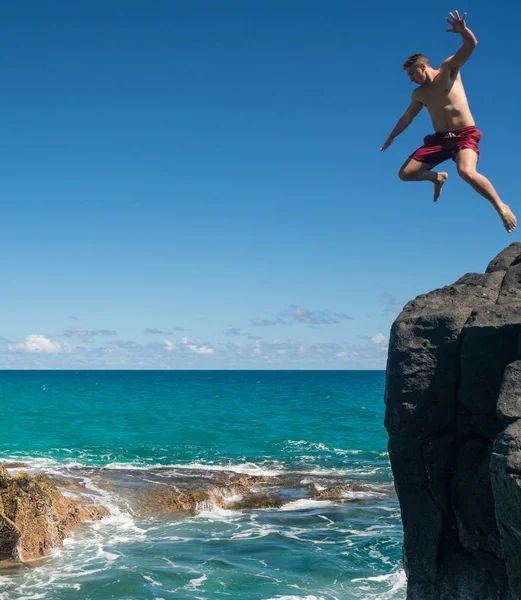 Fitter junger Mann springt am Strand von Lumahai ins Meer — Stockfoto