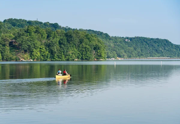 Pareja remando en canoa amarilla en lago arbolado —  Fotos de Stock