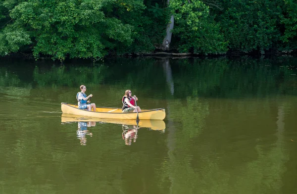 Casal remando em canoa amarela no lago arborizado — Fotografia de Stock