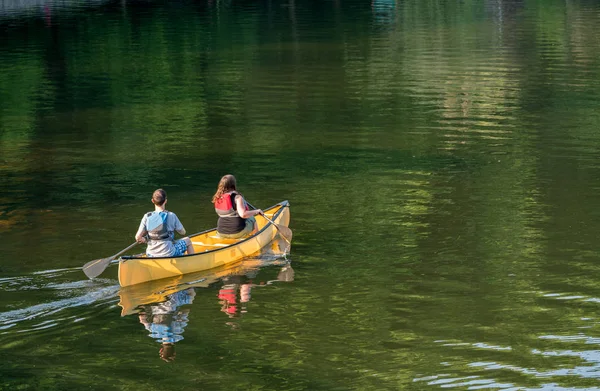 Couple pagayant en canot jaune sur un lac bordé d'arbres — Photo