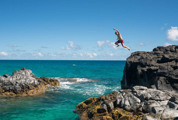 Fit young man jumps into ocean at Lumahai beach Kauai