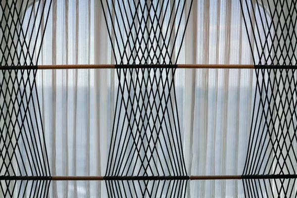 Net curtains on window with rope pattern