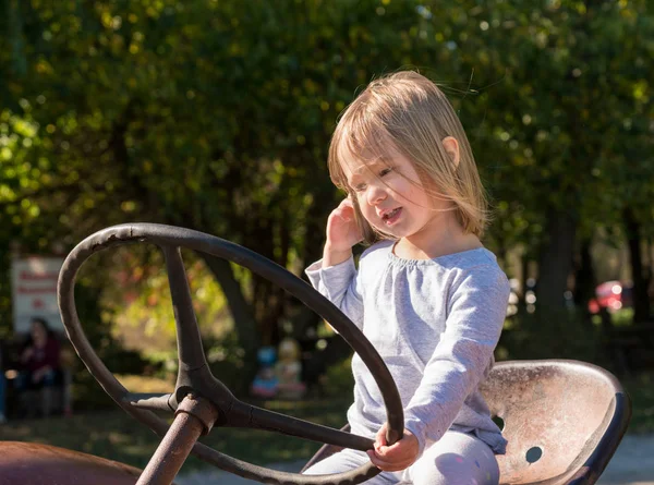 Young girl driving an old tractor on farm — Stock Photo, Image