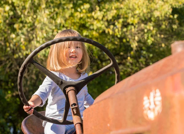 Junges Mädchen fährt alten Traktor auf Bauernhof — Stockfoto