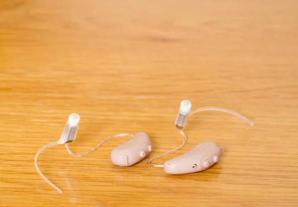 Gros plan d'une paire de minuscules aides auditives modernes sur une table de chevet — Photo