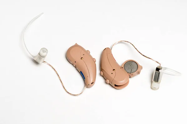 Close up of a pair of tiny modern hearing aids on white background — Stock Photo, Image