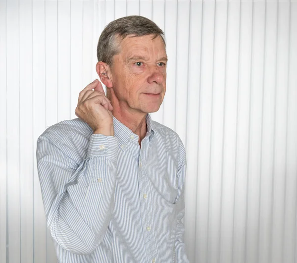 Primer plano de un audífono moderno diminuto con un hombre mayor —  Fotos de Stock