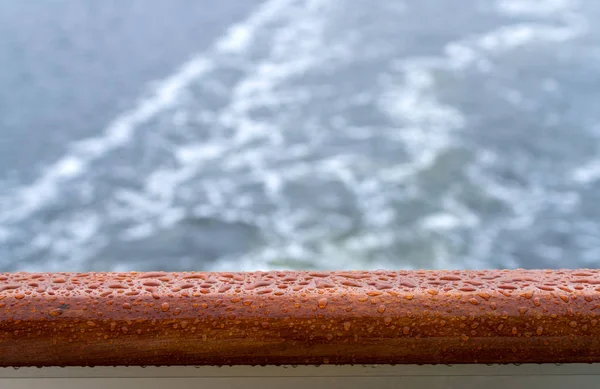 Raindrops on teak rail of cruise ship at sea — Stock Photo, Image