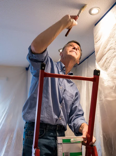 Senior adult man painting ceiling of kitchen — Stock Photo, Image