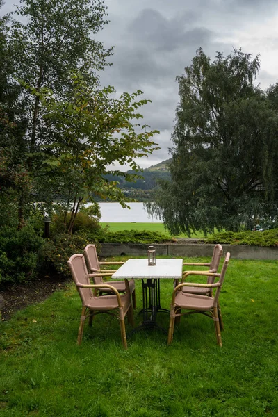 Стол и стулья на лужайке у озера в холодный осенний день — стоковое фото