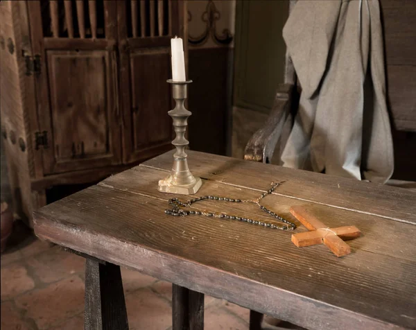 Древний стол со свечами, четками и крестом в комнате священника — стоковое фото
