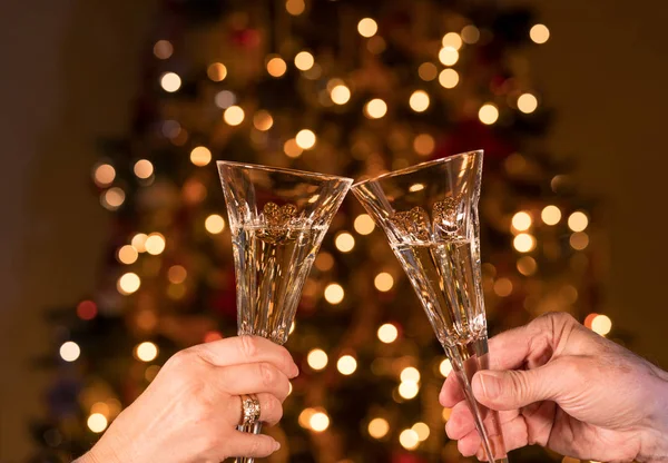 Champán en dos flautas de cristal contra las luces del árbol de Navidad — Foto de Stock